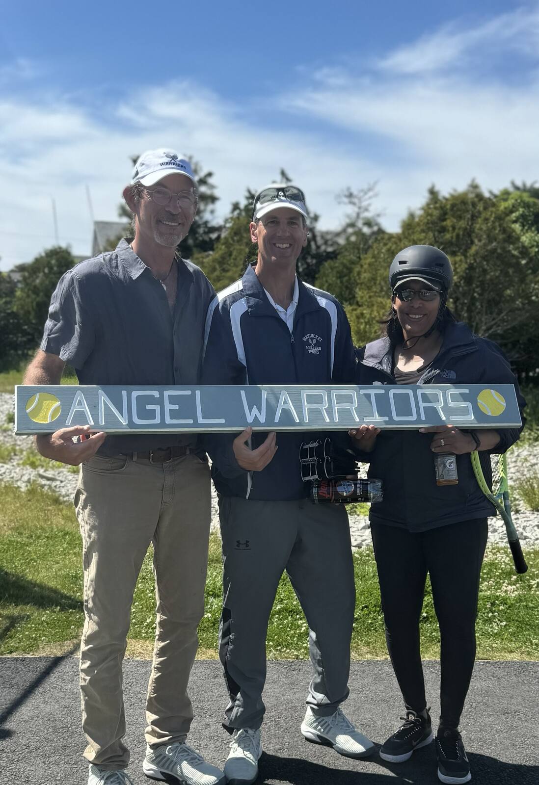Three coaches holding a painted Angel Warriors corner board
