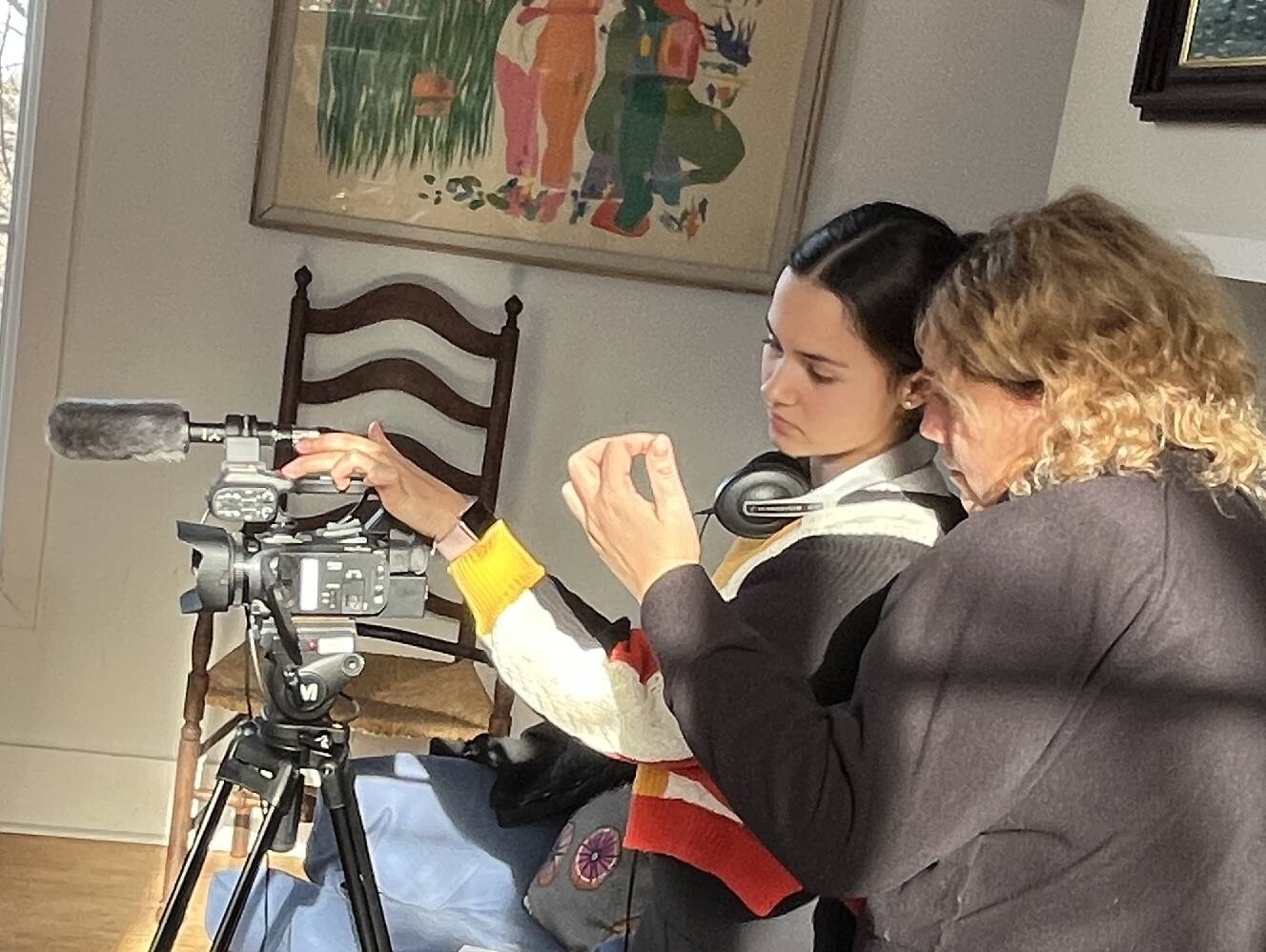 Two teenagers setting up a video camera on a tripod indoors