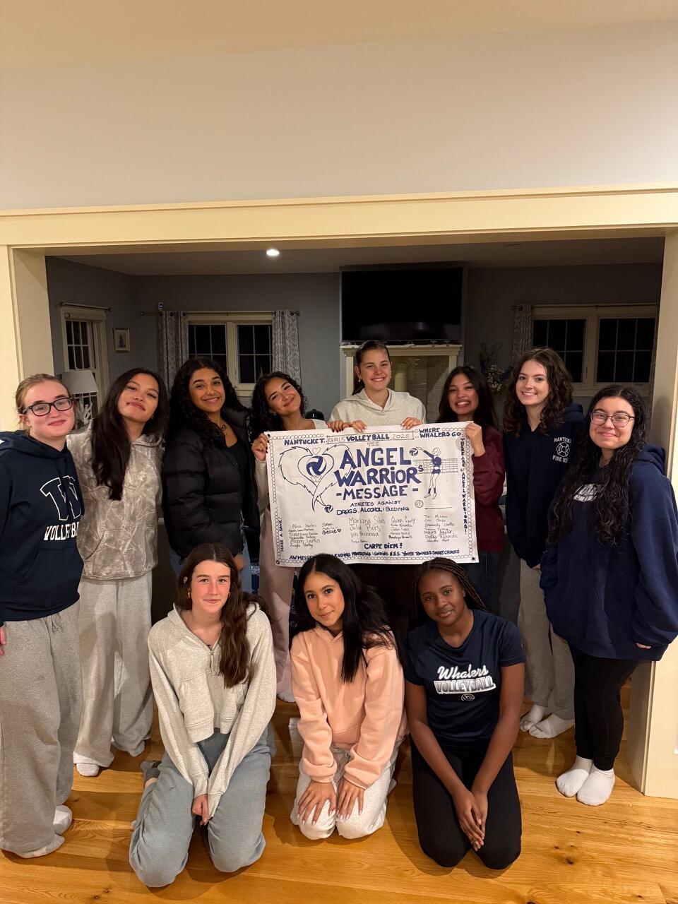 A group of teenagers indoors holding a printed copy of the Angel Warrior Message