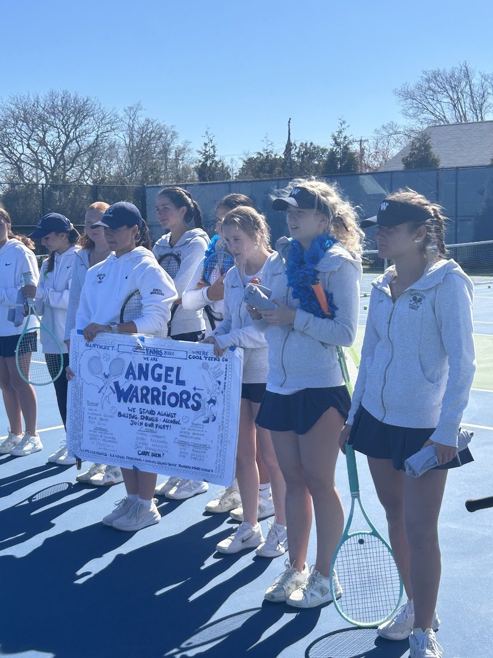 The Nantucket tennis team with their Angel Warriors banner at Great Harbor.